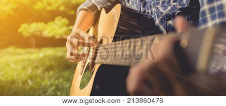 woman playing guitar at public park woman's hands playing acoustic guitar close up. banner panoramic crop for copy space.