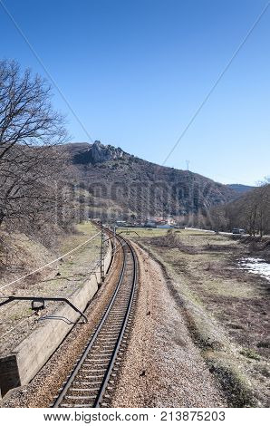 Iberian gauge railway track between Leon and Gijon, on its way through La Pola de Gordon, Leon Province, Spain. In the background can be seen the town of Puente de Alba