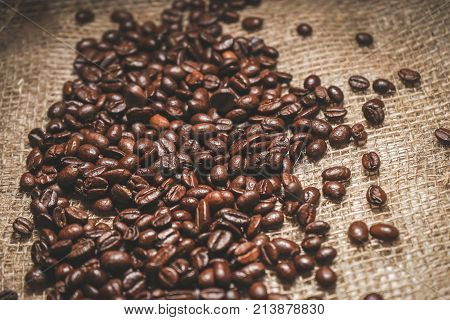 a large pile of brown flavored coffee beans is scattered on a bag