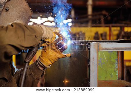 Welder for his work. Welding sparks on production background