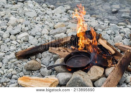 Cooking Sausages In Cast Iron Skillet On Campfire While Camping. Good And Positive Campfire Food.