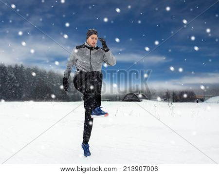 fitness, sport, people, exercising and healthy lifestyle concept - young man exercising and warmig up in winter outdoors