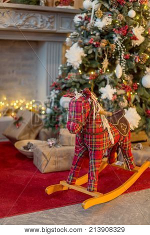 Red rocking horse, cockhorse in a christmas interior on the background of a Christmas tree and Christmas lights