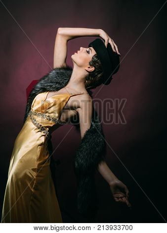 Look and retro style pinup. Pin up pretty fashion model pose on burgundy background. Girl in yellow dress hat and fur. Woman with stylish retro hair and makeup. Beauty and vintage fashion.
