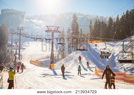 Bukovel, Ukraine - December 22, 2016: Skiers on the ski lift riding up at ski resort with beautiful background of snow-covered slopes, forests, hills in Bukovel, Ukraine