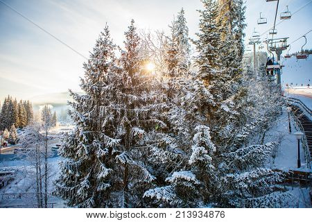 Skiers on the ski lift riding up at ski resort with beautiful background of snow-covered slopes, forests, hills in Bukovel, Ukraine