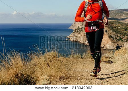 athlete runner running along sea shore in mountain marathon