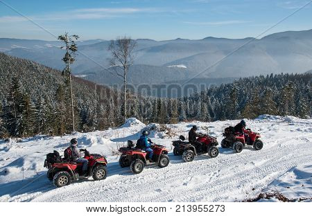 Four Atv Riders On Off-road Quad Bikes On Snow At Top Of The Mountain In Winter