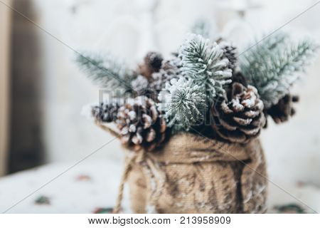 Winter holidays background of pine cones powdered with artificial snow and white downy shawl. Merry Christmas brown backdrop.