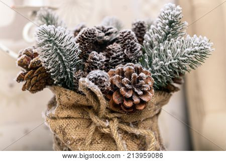 Winter holidays background of pine cones powdered with artificial snow and white downy shawl. Merry Christmas brown backdrop.
