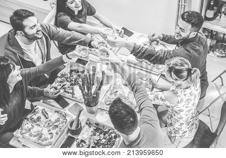Happy friends toasting beers and eating pizza at home - Young people having fun drinking and laughing together - Dinnerparty and friendship concept - Main focus on right guys hands - Retro editing