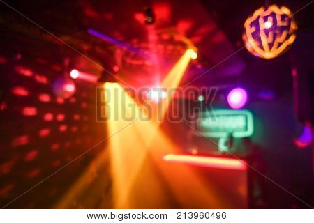 Blurred disco club with original laser color lights and disco ball - Defocused image - Concept of nightlife with cocktails music entertainment - Warm filter with blurry bokeh