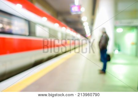 Blurred man waiting for high speed train in railwaystation - Defocused image - Original lights - Transportation work and travel concept