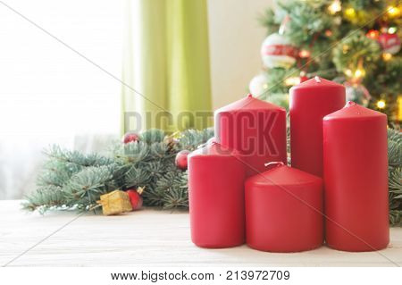 Red Christmas Candles On White Wooden Plank Against Christmas Tree In Living Room