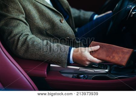 close up of the businessman in the car with a purse.