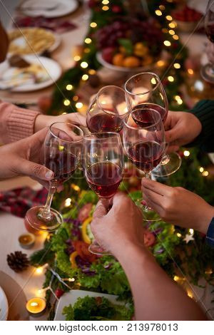 Group of people celebraiting New Year. They are drinking red wine