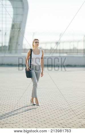 The image of a business woman goes on the street at sunset