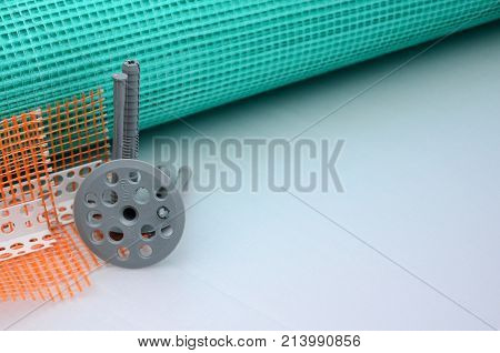 A Set Of Construction Items For The Insulation Of Walls. Plastic Dowels, A Roll Of Mesh For The Insu