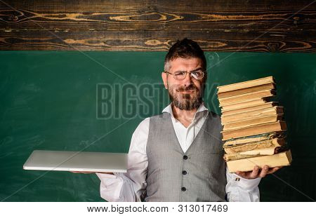 Modern Education. Smiling Male Student Holds Traditional Textbook And Reading E-book. Book Vs E-book