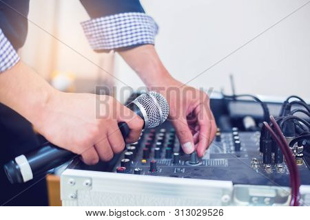 Microphone In Hand And Adjust An Audio Mixer Controller In The Control Room, Sound Mixer Control For