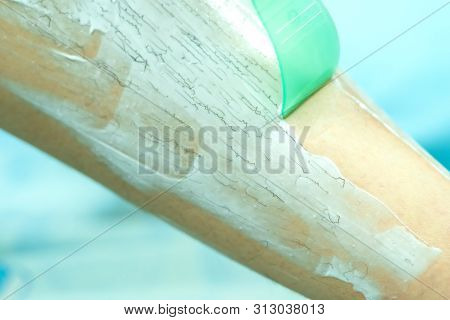Woman Epilating Leg With Depilation Cream And Spatula. Scrubs Hair Removal Cream.