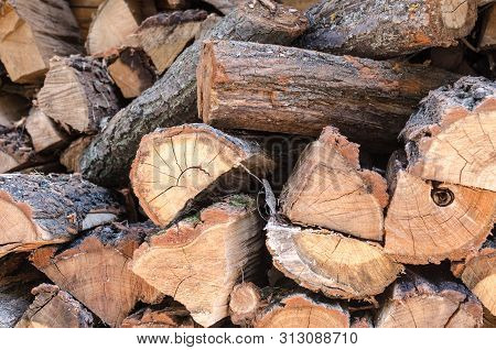 Pile Of Stacked Triangle Firewood Prepared For Fireplace And Boiler. Background With Pile Of Firewoo