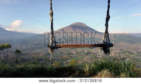 Empty Swing And Beautiful Mountain Morning View. Natural Wooden Swing Hanging Against  Top Of Blue M
