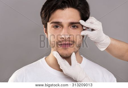 Facial Massage, Wrinkles Prevention. Beautician Massaging Her Face Of Young Handsome Man