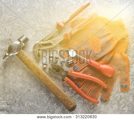 Working Tool On A Gray Concrete Surface. Work Gloves, Hammer, Nippers, Screwdriver, Pliers, Screwdri