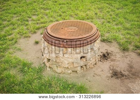 Old Rusty Round Sewerage Hatchway With Foundation.