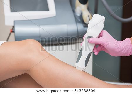 Specialist makes skin tone measurements on a womans leg, to determine the settings for hair laser depilation. First step before depilation. Cosmetology and SPA concept