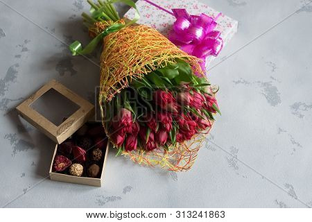 Flowers, A Box With A Gift And A Box Of Chocolates On A Gray Background