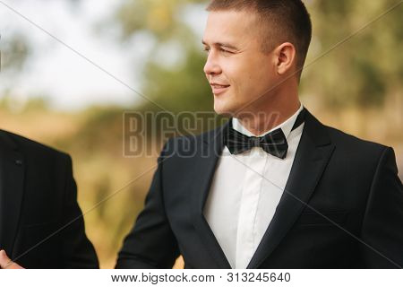 Young Man Walking In The Park. Handsome Groom In Black Suit