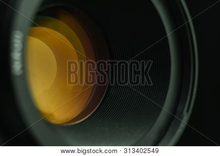 Beautiful Camera Lens  With Yellow Light Of Glass On A Black Background.