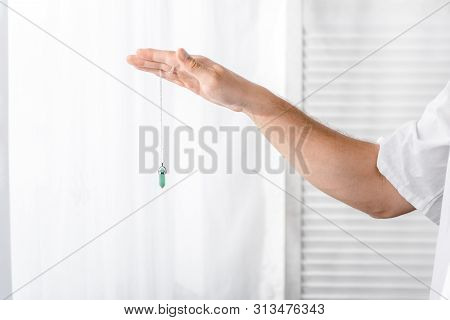 Cropped View Of Hypnotist Holding Green Stone In Clinic