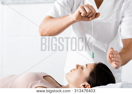 Cropped View Of Hypnotist Standing Near Woman And Holding Green Stone Above Her Face