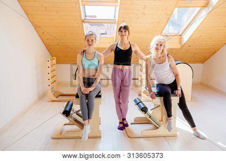 Portrait Of Three Different Generation Women Team In Small Cozy Pilates Studio With Equipment On Bac