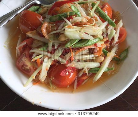 Close-up On Thai Papaya Salad On White Plate Over Wooden Table - Healthy Asian Food Concept, Angle V