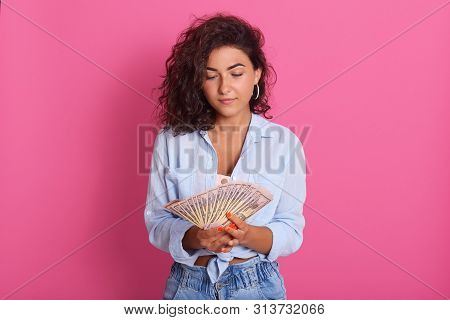 Image Of Thounghtful Young Brunette Woman Wearing Blue Shot And Jeans Standing Isolated Over Pink St