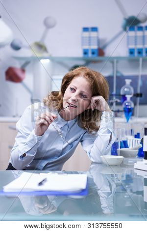 Portrait Of Middle Age Woman Playing With Her Glasses While Sitting At Her Office In Hospital Labora