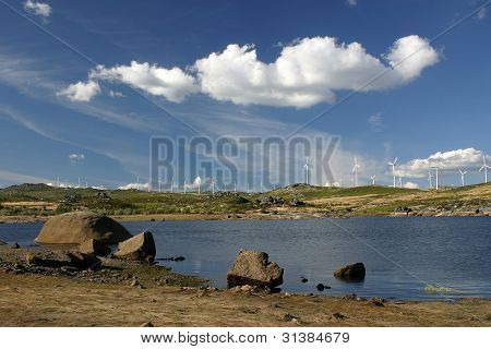 paesaggio con lago nuvole e aerogeneratori in background