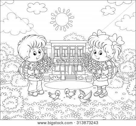 Happy Schoolchildren With Big Bouquets Of Flowers And Schoolbags Standing In Front Of Their School O