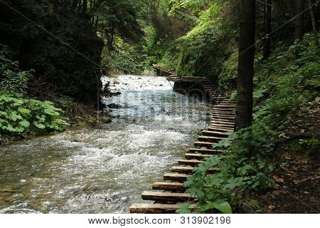A Wooden Footbridge Running Along A Larger Stream In The Slovak Paradise National Park