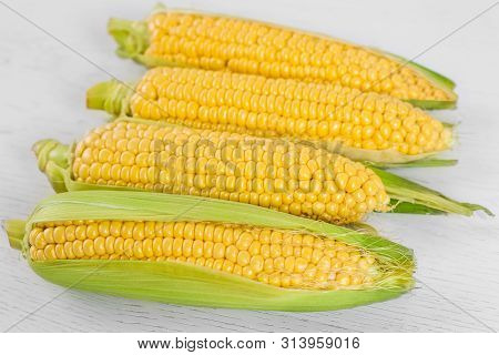 Fresh Corn Cobs On Wooden White Background. Сlose Up