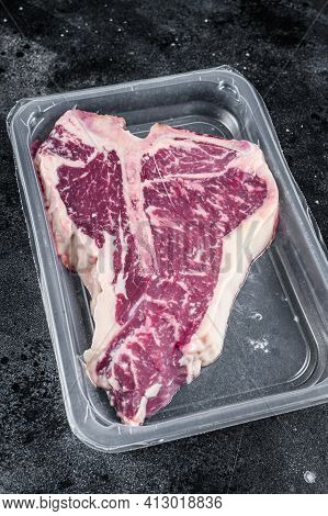 T-bon Raw Beef Steak In Vacuum Packaging. Black Background. Top View