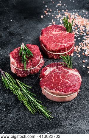 Fillet Mignon Tenderloin Raw Meat Beef Steaks On Butchery Table. Black Background. Top View