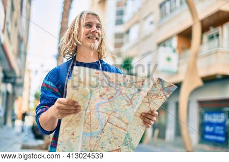 Young scandinavian tourist man smiling happy using map at the city.