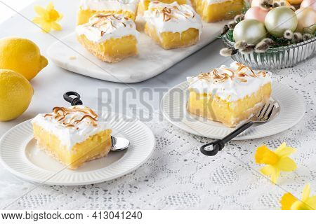 Close Up Of Two Servings Of Lemon Meringue Squares With More Slices In Behind And An Easter Egg Deco