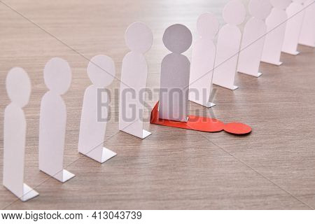 Concept Of Social Exclusion With Many Little White Paper Men Lined Up And One Stepping On A Differen