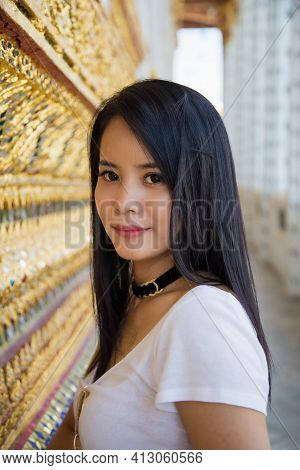 Portrait Asian Woman In A White T-shirt Lookingat A Camera Next To A Golden Thai Tradition Patterned